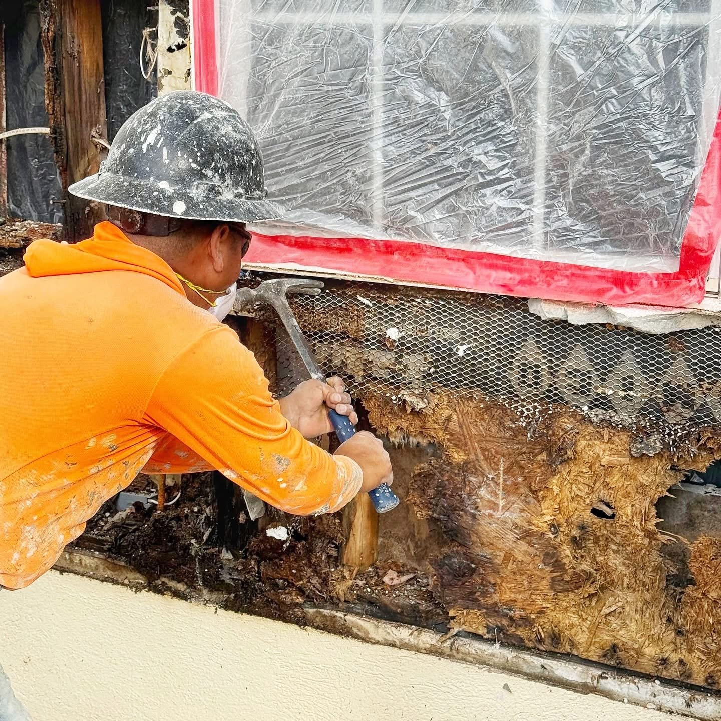 Worker performing demolition and surface prep with protective sheeting