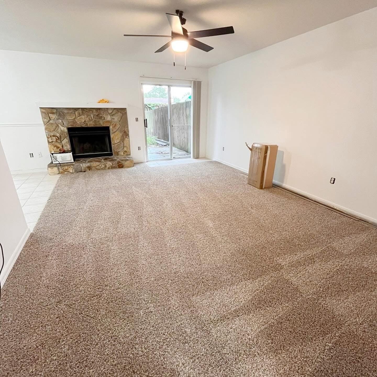 Living room with plush carpet, ceiling fan and fireplace after remodel