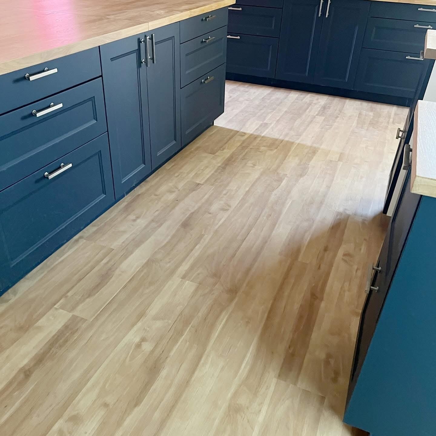 Kitchen remodel with navy blue cabinets and wood-look vinyl flooring