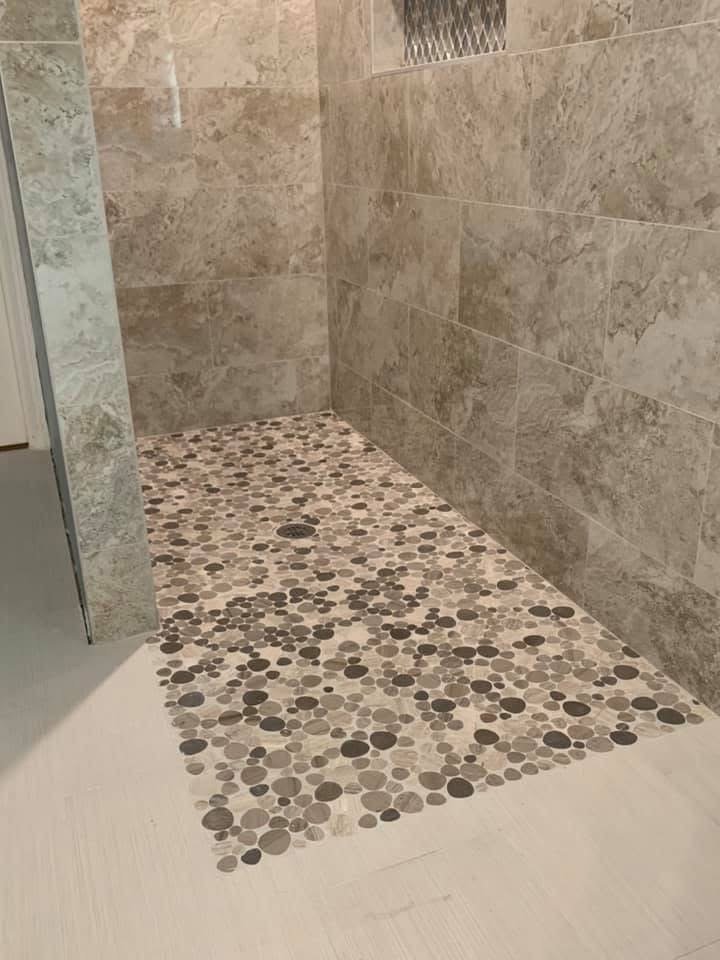 Walk-in shower with large-format wall tile and pebble stone floor